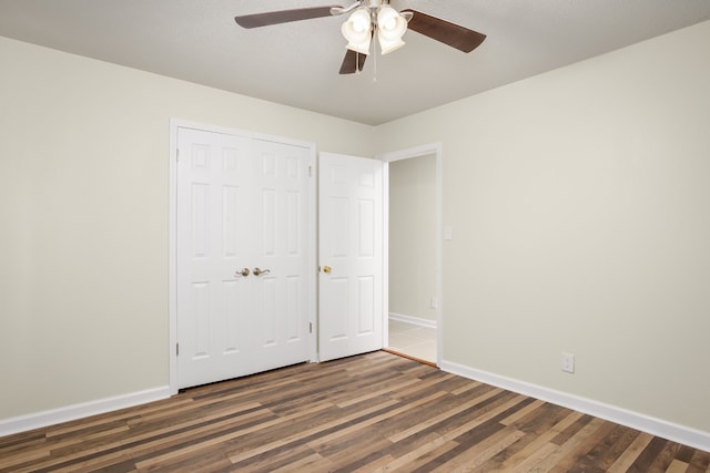 unfurnished bedroom featuring ceiling fan, a closet, dark wood-type flooring, and a textured ceiling