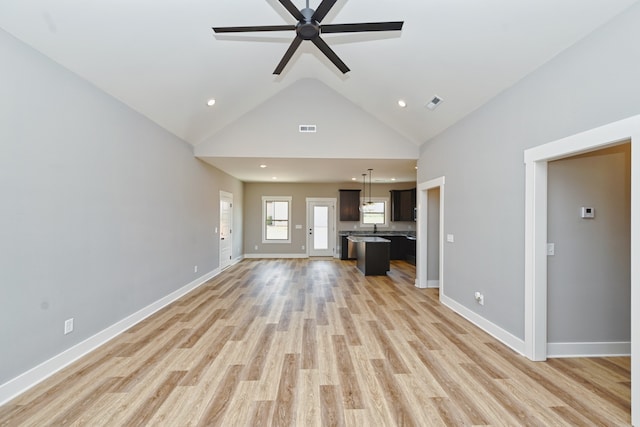 unfurnished living room with light hardwood / wood-style floors, high vaulted ceiling, ceiling fan, and sink