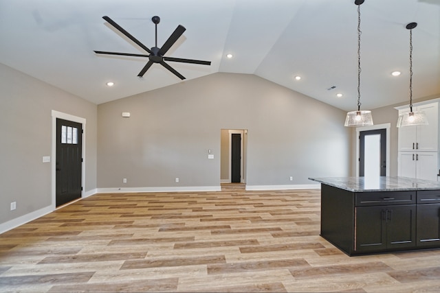 kitchen featuring light hardwood / wood-style floors, vaulted ceiling, ceiling fan, and light stone counters