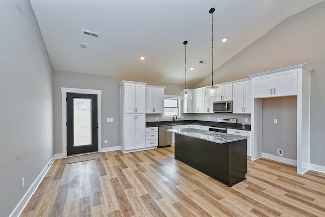 kitchen with white cabinets, a center island, appliances with stainless steel finishes, and a wealth of natural light