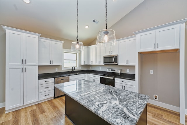 kitchen featuring white cabinets, a kitchen island, lofted ceiling, and appliances with stainless steel finishes