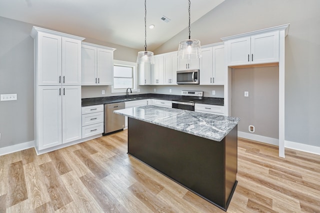 kitchen featuring a center island, white cabinets, vaulted ceiling, and appliances with stainless steel finishes