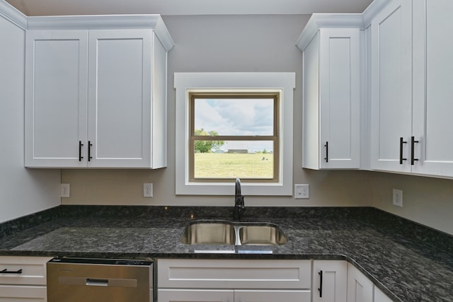 kitchen with dark stone counters, white cabinetry, stainless steel dishwasher, and sink