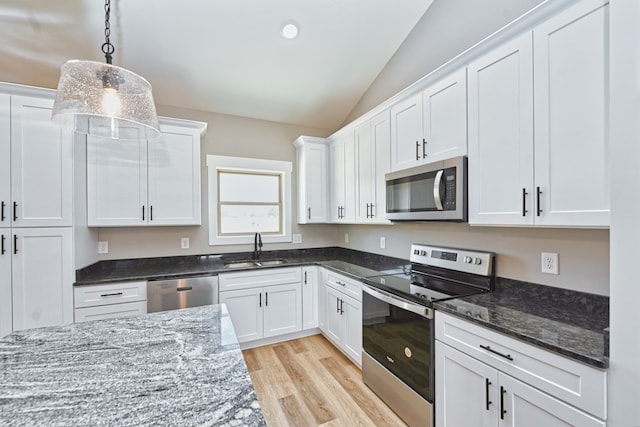 kitchen with pendant lighting, white cabinetry, lofted ceiling, and stainless steel appliances