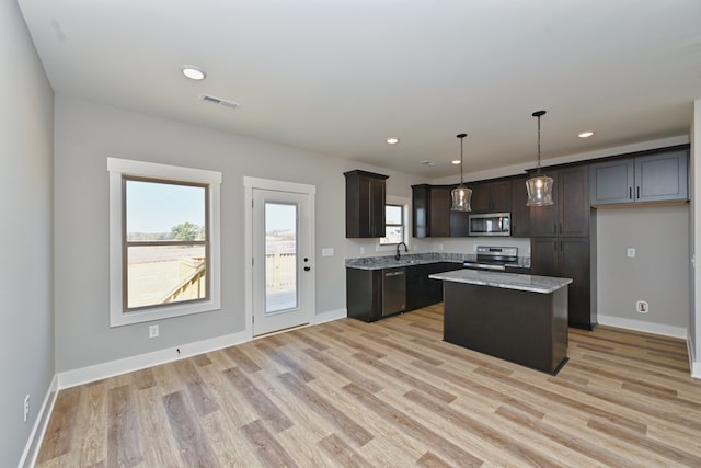 kitchen featuring dark brown cabinetry, a center island, stainless steel appliances, pendant lighting, and light wood-type flooring