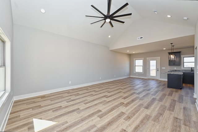 unfurnished living room featuring ceiling fan, light wood-type flooring, and high vaulted ceiling