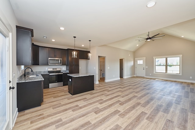 kitchen featuring stainless steel appliances, decorative light fixtures, light hardwood / wood-style flooring, a center island, and lofted ceiling