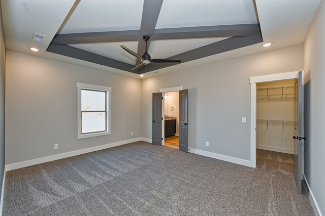 unfurnished bedroom with ensuite bath, ceiling fan, a walk in closet, a closet, and carpet