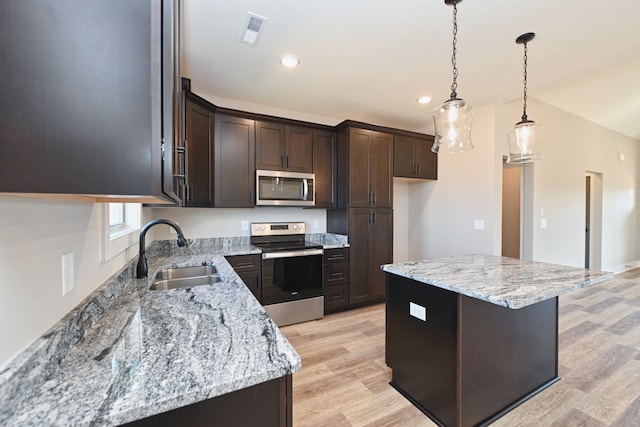 kitchen with light stone countertops, sink, a kitchen island, and stainless steel appliances