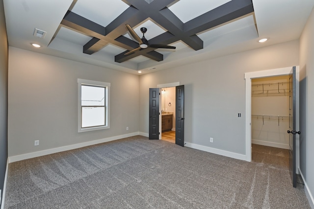 unfurnished bedroom with carpet, coffered ceiling, a walk in closet, ceiling fan, and a closet