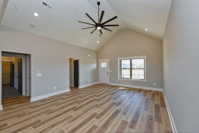 unfurnished living room with ceiling fan, light wood-type flooring, and high vaulted ceiling