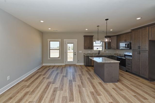 kitchen featuring sink, hanging light fixtures, stainless steel appliances, light hardwood / wood-style flooring, and a kitchen island