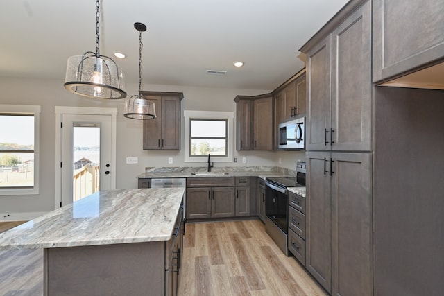 kitchen featuring plenty of natural light, a kitchen island, light hardwood / wood-style flooring, and appliances with stainless steel finishes