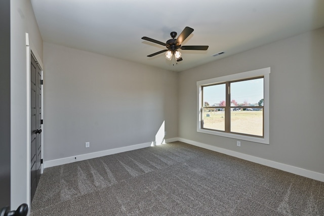 spare room featuring dark carpet and ceiling fan