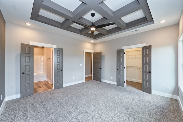 unfurnished bedroom with carpet flooring, beam ceiling, a spacious closet, and coffered ceiling