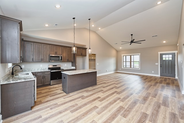 kitchen with pendant lighting, sink, light hardwood / wood-style flooring, a kitchen island, and stainless steel appliances