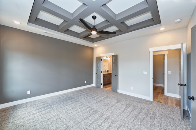 unfurnished bedroom with carpet flooring, beamed ceiling, ensuite bath, and coffered ceiling