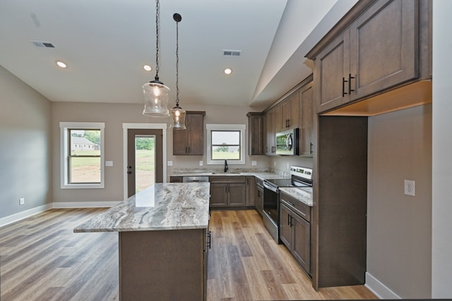 kitchen with lofted ceiling, hanging light fixtures, light wood-type flooring, appliances with stainless steel finishes, and a kitchen island