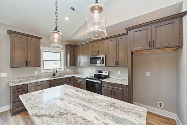 kitchen with appliances with stainless steel finishes, light stone counters, pendant lighting, and sink