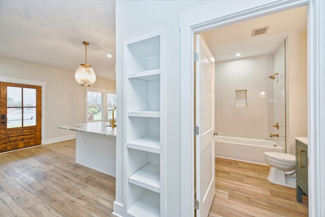 full bathroom with built in shelves, vanity, bathing tub / shower combination, hardwood / wood-style floors, and toilet