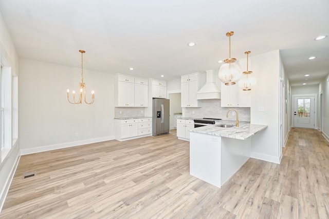 kitchen featuring white cabinetry, premium range hood, kitchen peninsula, stainless steel fridge, and light wood-type flooring