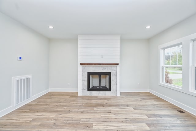 unfurnished living room featuring a large fireplace and light wood-type flooring