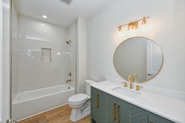 full bathroom featuring hardwood / wood-style floors, tiled shower / bath combo, toilet, and vanity