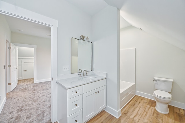 bathroom featuring toilet, hardwood / wood-style floors, vanity, and vaulted ceiling