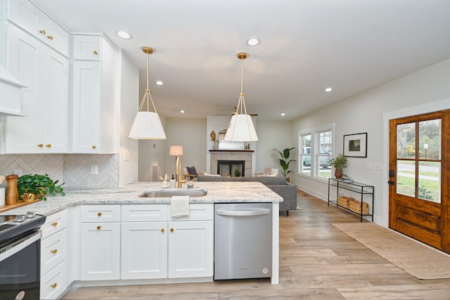 kitchen with white cabinets, a fireplace, appliances with stainless steel finishes, and light hardwood / wood-style flooring