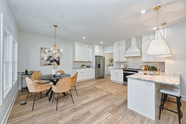 kitchen with custom exhaust hood, sink, light hardwood / wood-style floors, white cabinetry, and stainless steel appliances