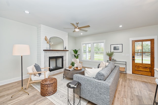 living room featuring a fireplace, light hardwood / wood-style flooring, a wealth of natural light, and ceiling fan