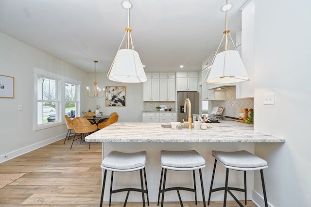 kitchen featuring pendant lighting, backsplash, light hardwood / wood-style floors, and white cabinetry