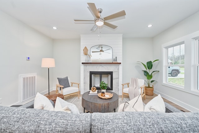 living room with ceiling fan, a high end fireplace, and hardwood / wood-style flooring