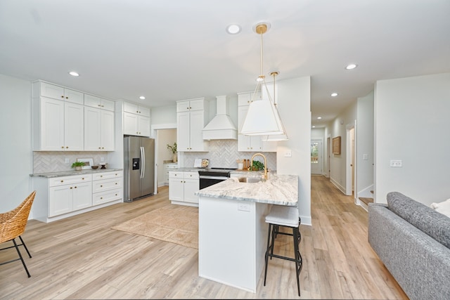 kitchen featuring kitchen peninsula, appliances with stainless steel finishes, custom exhaust hood, sink, and white cabinetry