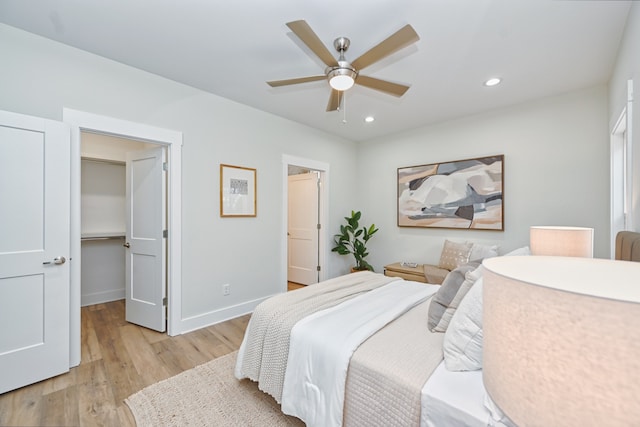 bedroom featuring ceiling fan, a spacious closet, and light hardwood / wood-style flooring