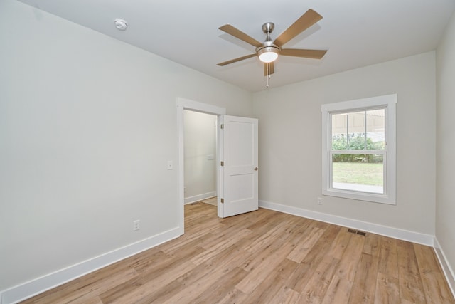 empty room with ceiling fan and light hardwood / wood-style flooring