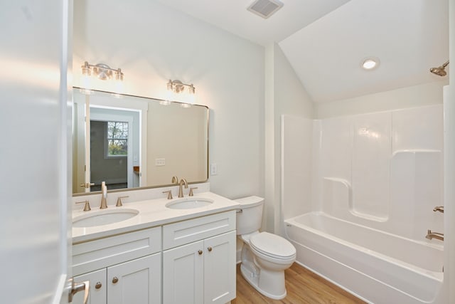 full bathroom with vanity, vaulted ceiling, hardwood / wood-style flooring, toilet, and shower / bath combination