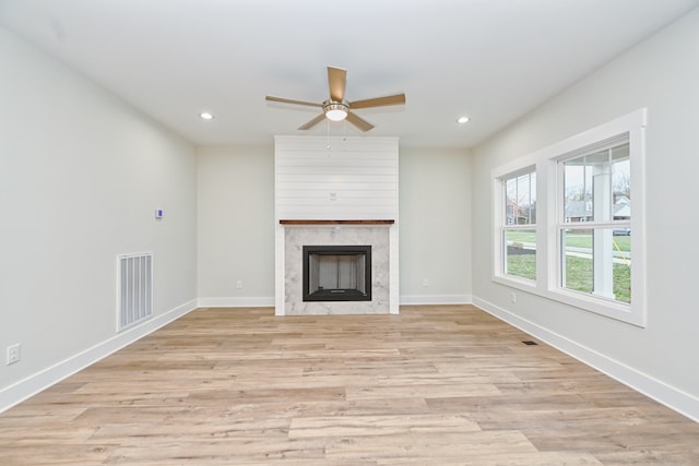 unfurnished living room featuring a fireplace, light hardwood / wood-style flooring, and ceiling fan