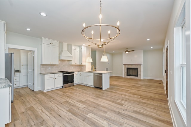 kitchen featuring white cabinetry, hanging light fixtures, stainless steel appliances, kitchen peninsula, and custom range hood