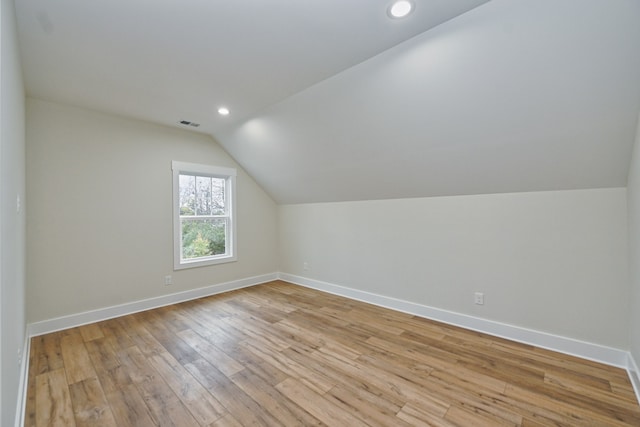 additional living space featuring lofted ceiling and light hardwood / wood-style flooring