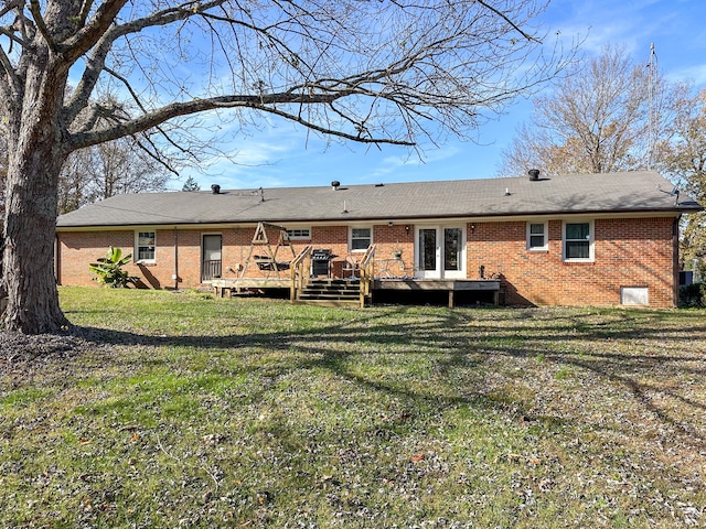 back of property with brick siding, french doors, a wooden deck, and a yard