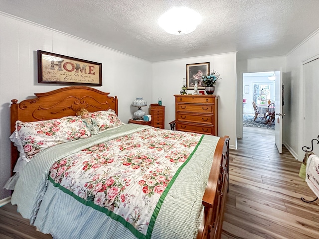 bedroom featuring ornamental molding, wood finished floors, and a textured ceiling