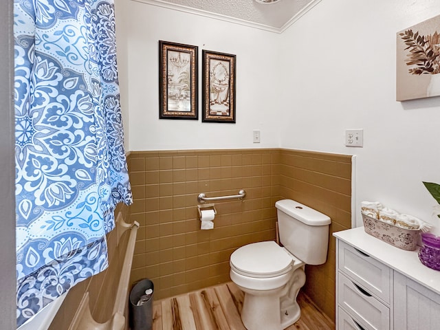 bathroom featuring tile walls, toilet, wainscoting, wood finished floors, and vanity