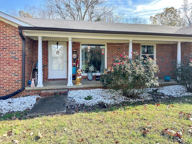 view of exterior entry featuring brick siding and a porch