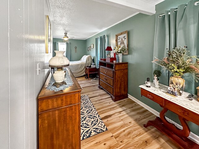 bedroom featuring a textured ceiling, wood finished floors, baseboards, and ornamental molding