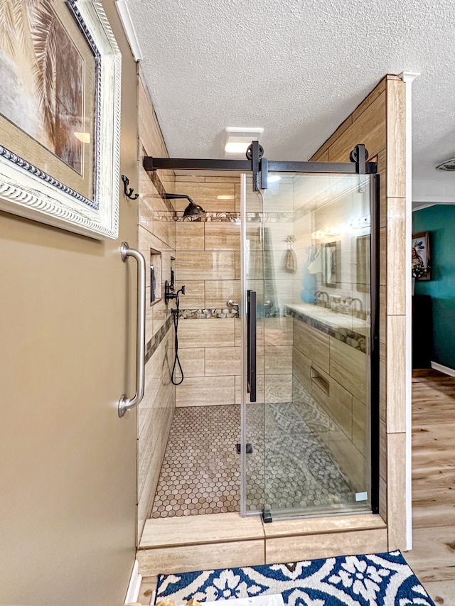 bathroom with wood finished floors, a stall shower, and a textured ceiling