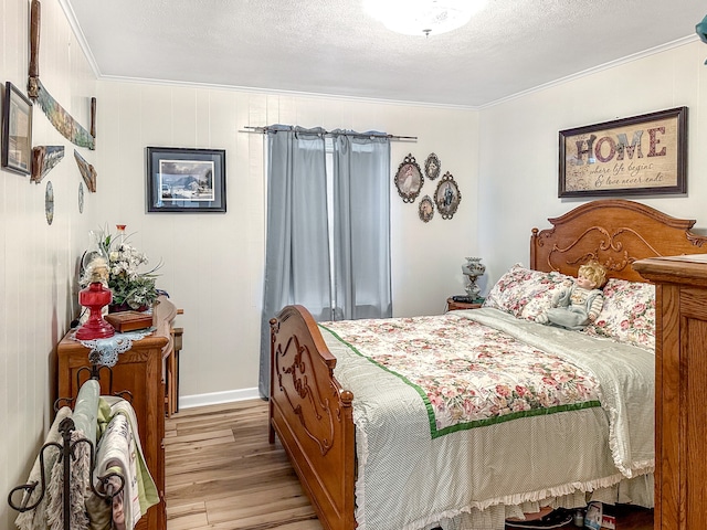 bedroom featuring ornamental molding, baseboards, light wood finished floors, and a textured ceiling