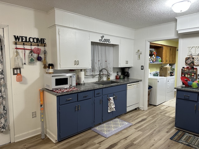 kitchen featuring washer and dryer, white appliances, blue cabinets, and a sink