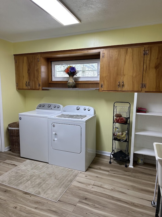 laundry area featuring washer and dryer, cabinet space, light wood-type flooring, and a textured ceiling