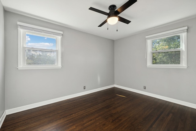 empty room featuring a wealth of natural light, ceiling fan, and dark hardwood / wood-style floors